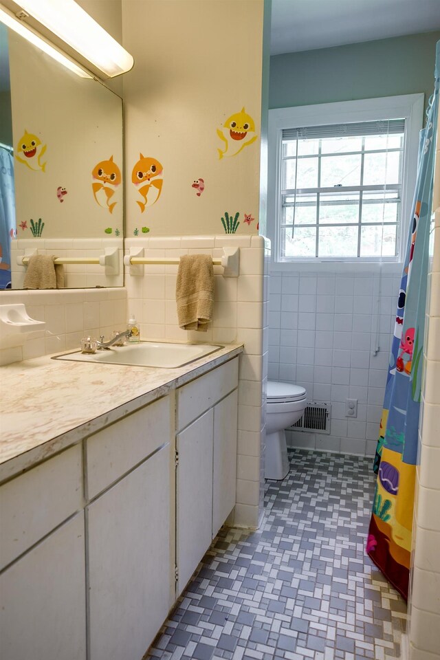312 N E St, Harrisburg, AR 72432 - bathroom featuring tile walls, toilet, vanity, a wainscoted wall, and a shower with shower curtain