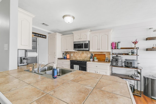 142 Peach St, Austin, AR 72007 - kitchen with stainless steel microwave, black electric range oven, a sink, white cabinets, and tasteful backsplash
