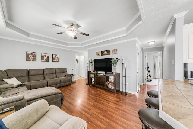 142 Peach St, Austin, AR 72007 - living room with a raised ceiling, a ceiling fan, crown molding, dark wood-style flooring, and baseboards