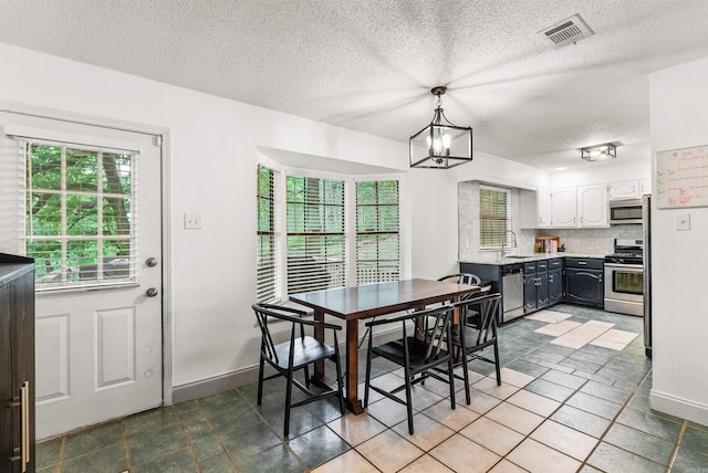 4 Desoto Forest Cv, Little Rock, AR 72211 - dining area with a chandelier, a textured ceiling, baseboards, and tile patterned floors