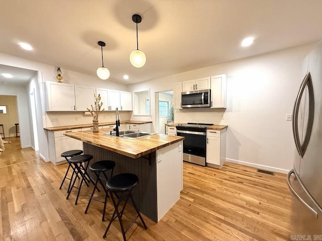 601 Clarence St, Mountain View, AR 72560 - kitchen featuring wood counters, appliances with stainless steel finishes, a sink, white cabinets, and a kitchen bar