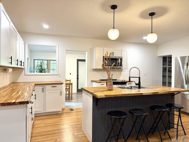 601 Clarence St, Mountain View, AR 72560 - kitchen with wooden counters, stainless steel appliances, a sink, light wood-type flooring, and a breakfast bar