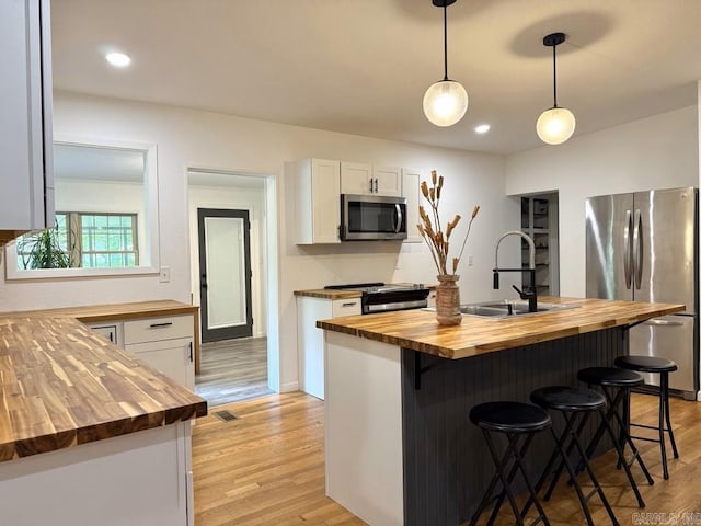 601 Clarence St, Mountain View, AR 72560 - kitchen with wood counters, stainless steel appliances, light wood finished floors, white cabinetry, and a sink
