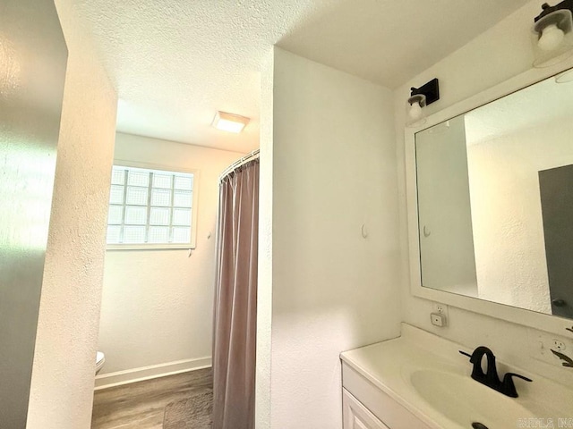 601 Clarence St, Mountain View, AR 72560 - full bath with wood finished floors, toilet, vanity, baseboards, and a textured wall