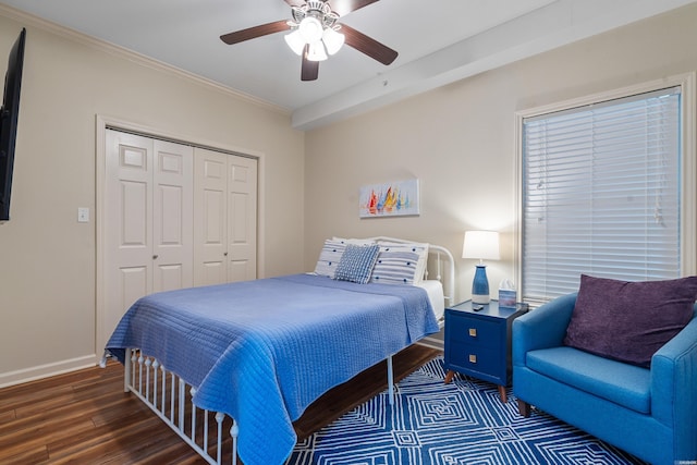 bedroom with wood finished floors, a closet, ornamental molding, baseboards, and ceiling fan