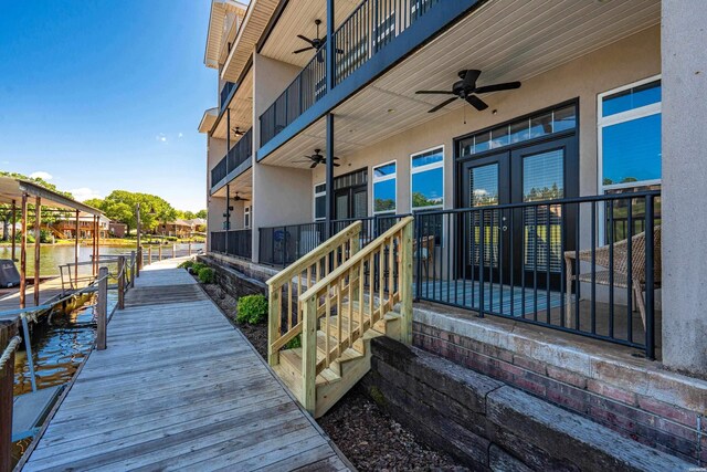 wooden terrace featuring ceiling fan, a boat dock, and french doors