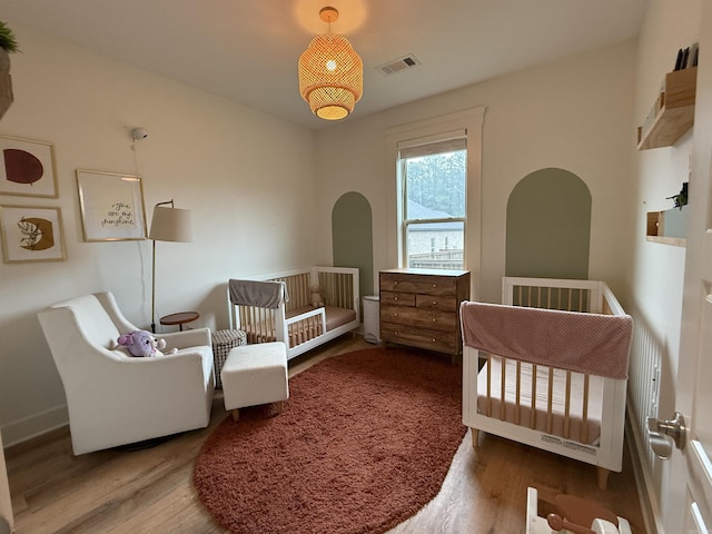 bedroom with wood finished floors and a nursery area