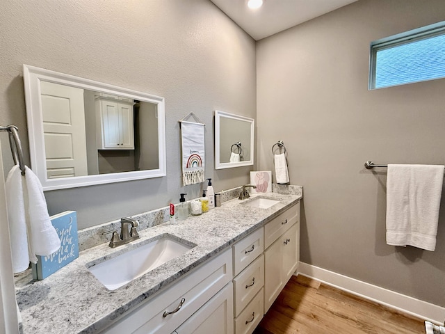 full bathroom featuring wood finished floors, double vanity, and baseboards