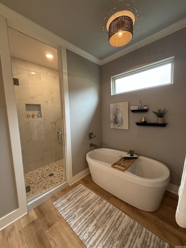 full bathroom with a stall shower, crown molding, a freestanding tub, wood finished floors, and baseboards