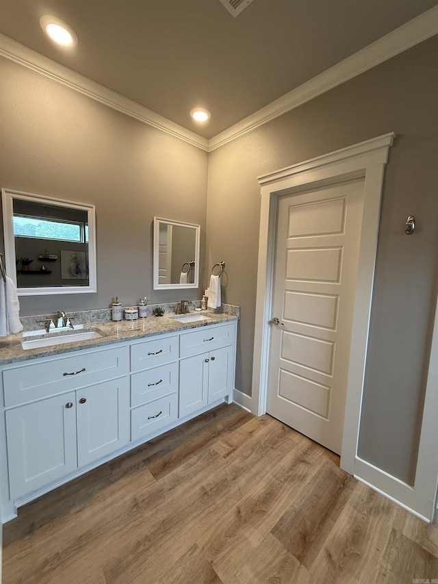 bathroom with crown molding, double vanity, and wood finished floors