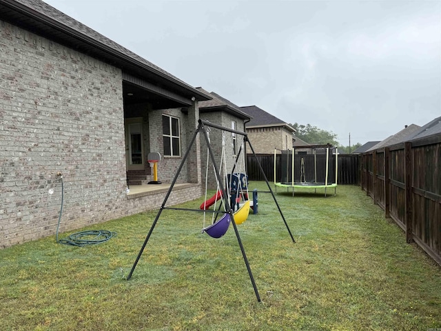 view of yard featuring a trampoline, a playground, and a patio area