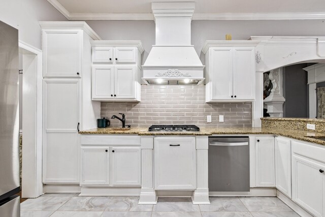 2724 Crooked Stick Dr, Benton, AR 72015 - kitchen featuring stainless steel appliances, premium range hood, light marble finish flooring, white cabinets, and decorative backsplash