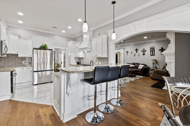 2724 Crooked Stick Dr, Benton, AR 72015 - kitchen featuring appliances with stainless steel finishes, premium range hood, arched walkways, open floor plan, and recessed lighting