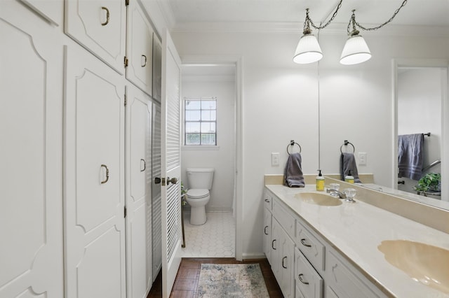 bathroom featuring crown molding, toilet, double vanity, wood finished floors, and baseboards