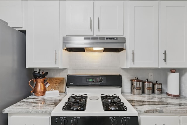 kitchen featuring white gas range, under cabinet range hood, tasteful backsplash, and white cabinets