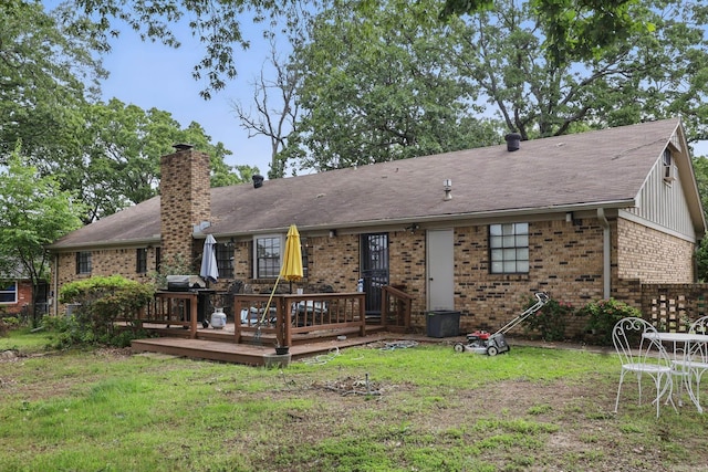 rear view of house with a chimney, brick siding, a wooden deck, and a lawn