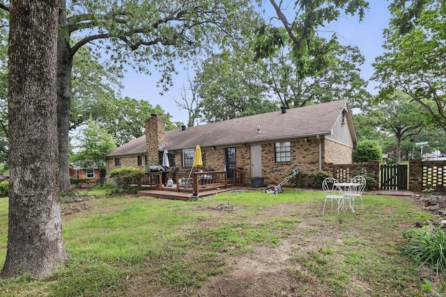rear view of property with a chimney, a deck, and brick siding