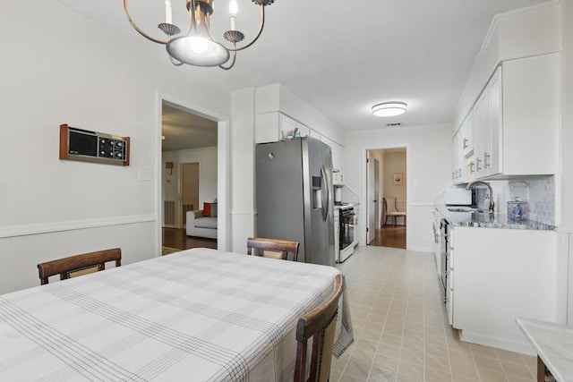 dining room featuring light floors, a chandelier, and baseboards