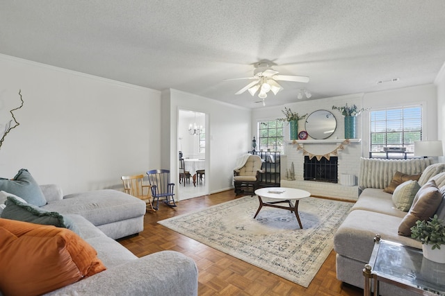 living area with ceiling fan, crown molding, a textured ceiling, a chandelier, and a brick fireplace
