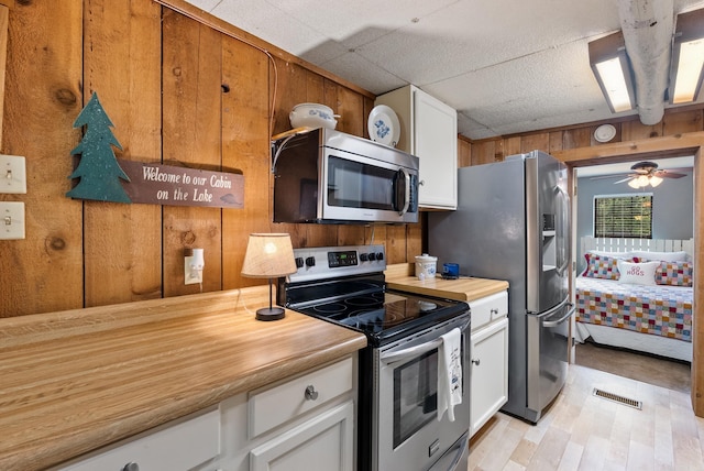 112 Fairchild Pt, Hot Springs, AR 71901 - kitchen featuring appliances with stainless steel finishes, wooden walls, white cabinets, light wood-type flooring, and ceiling fan