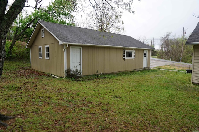 view of side of property with a lawn and roof with shingles