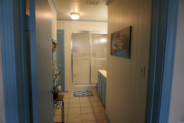 full bathroom with a stall shower, tile patterned floors, vanity, and wooden walls