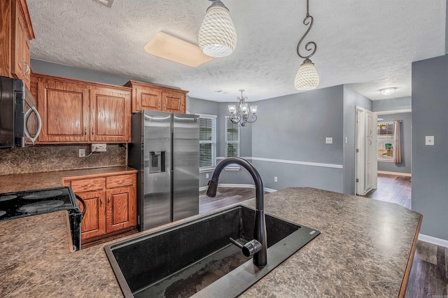 kitchen featuring appliances with stainless steel finishes, dark countertops, dark wood-style flooring, a sink, and healthy amount of natural light