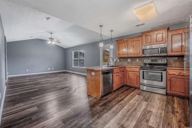 kitchen featuring stainless steel appliances, a peninsula, a sink, a textured ceiling, and dark wood-style flooring