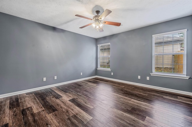 empty room featuring plenty of natural light, dark wood-style flooring, ceiling fan, and a textured ceiling