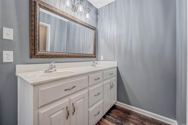 full bath featuring wood finished floors, baseboards, double vanity, and a textured wall