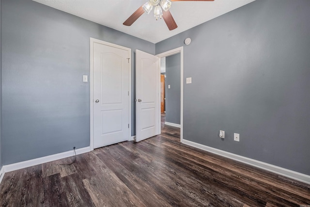 unfurnished bedroom featuring baseboards, dark wood-style floors, and ceiling fan
