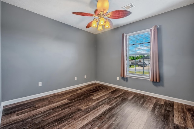 spare room featuring dark wood finished floors, a ceiling fan, and baseboards
