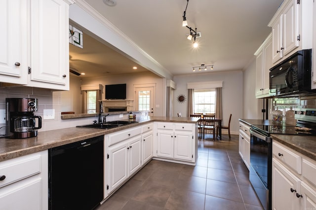 kitchen with black appliances, a sink, white cabinets, dark countertops, and a peninsula