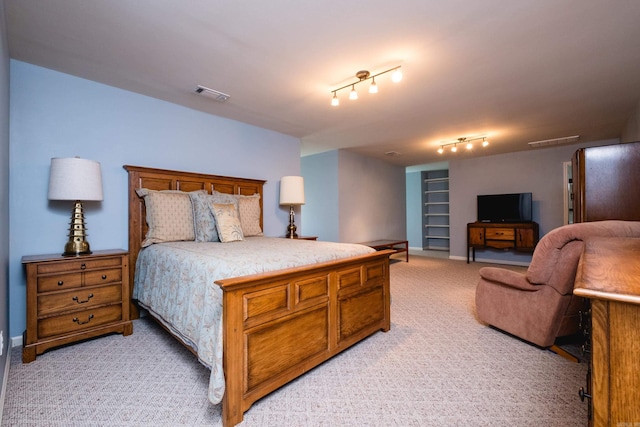 bedroom featuring light colored carpet and track lighting