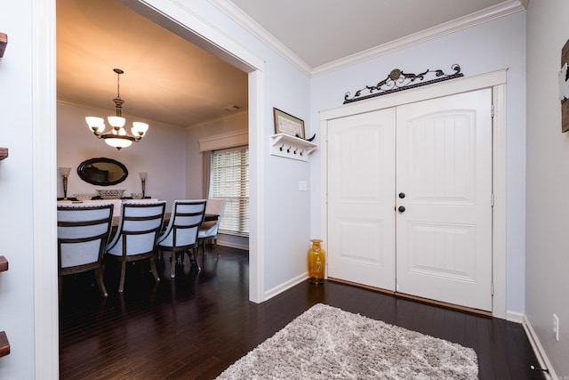 entrance foyer with ornamental molding, a chandelier, dark wood-style floors, and baseboards
