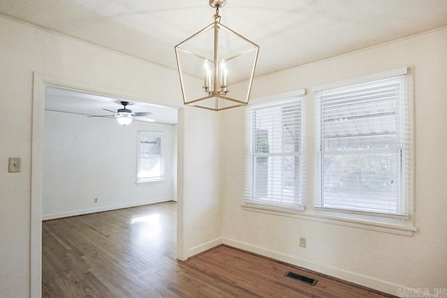 unfurnished dining area with a chandelier, wood finished floors, baseboards, and ceiling fan
