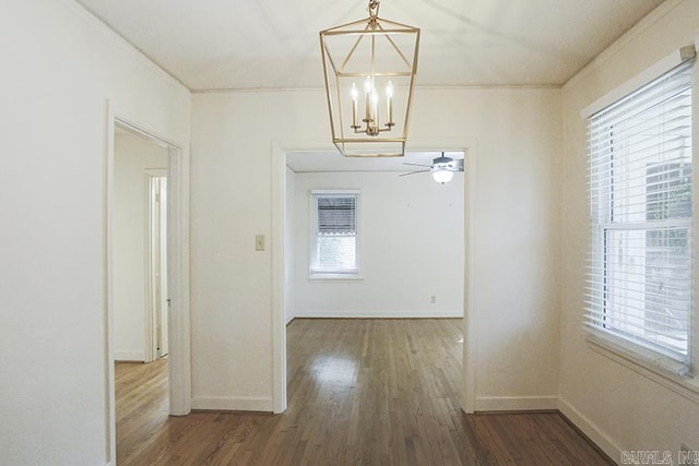 unfurnished dining area with wood finished floors, baseboards, a chandelier, ornamental molding, and ceiling fan