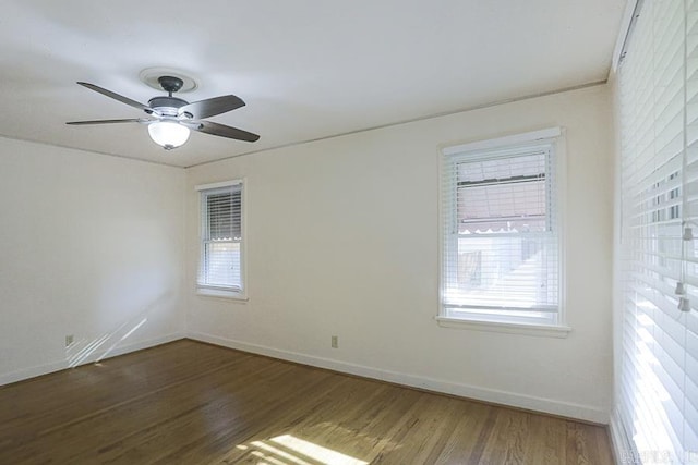 spare room featuring baseboards, wood finished floors, and a ceiling fan