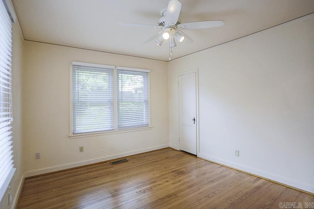 empty room featuring wood finished floors, a ceiling fan, and baseboards