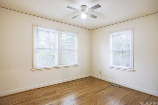 spare room featuring baseboards, wood finished floors, and ceiling fan