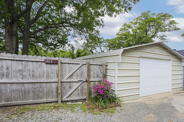 detached garage featuring fence and a gate