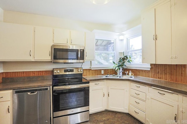 kitchen featuring stainless steel appliances, dark countertops, a sink, and plenty of natural light