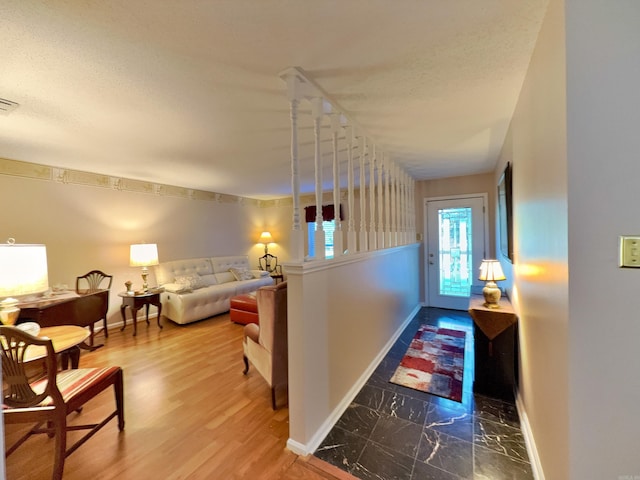 corridor featuring baseboards, a textured ceiling, and marble finish flooring