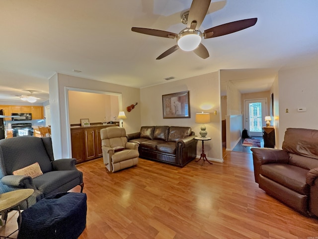 living room featuring ceiling fan, light wood-type flooring, and baseboards