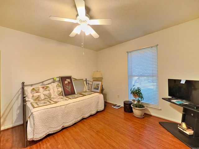 bedroom featuring wood finished floors, baseboards, and a ceiling fan