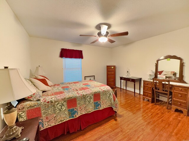 bedroom featuring wood finished floors, an office area, and ceiling fan