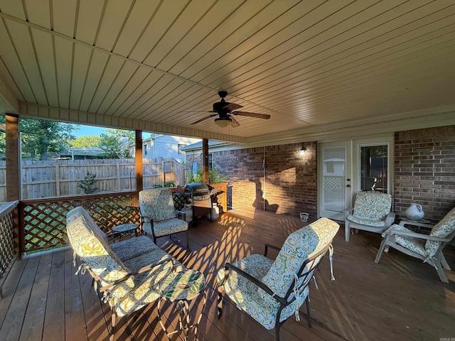 wooden terrace with a ceiling fan, fence, and grilling area