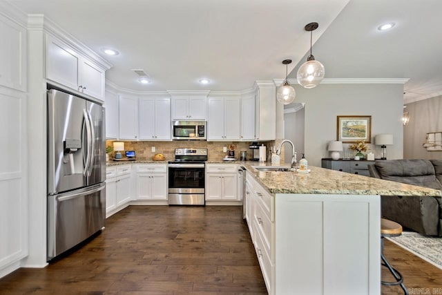 kitchen featuring appliances with stainless steel finishes, a peninsula, a sink, white cabinetry, and ornamental molding