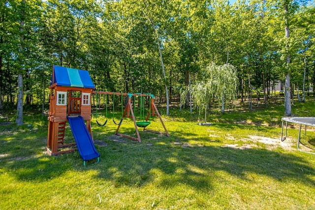 view of play area featuring a trampoline, a yard, and view of scattered trees