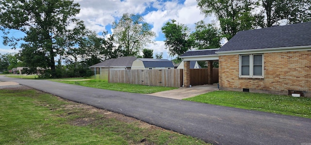 view of side of property featuring brick siding, a shingled roof, and concrete driveway